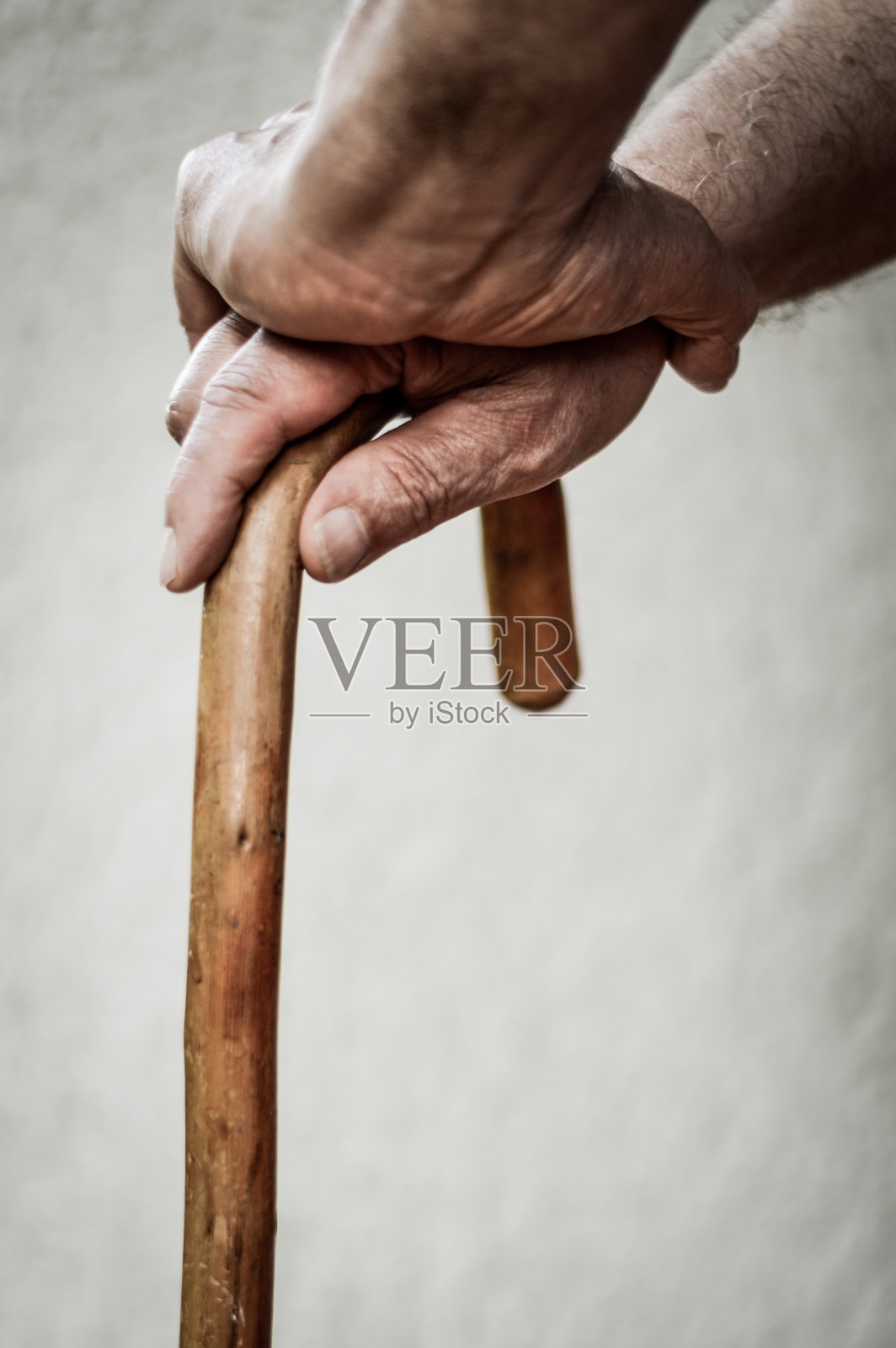 高级男子的手在木制手杖的特写。选择性地关注手指。照片摄影图片