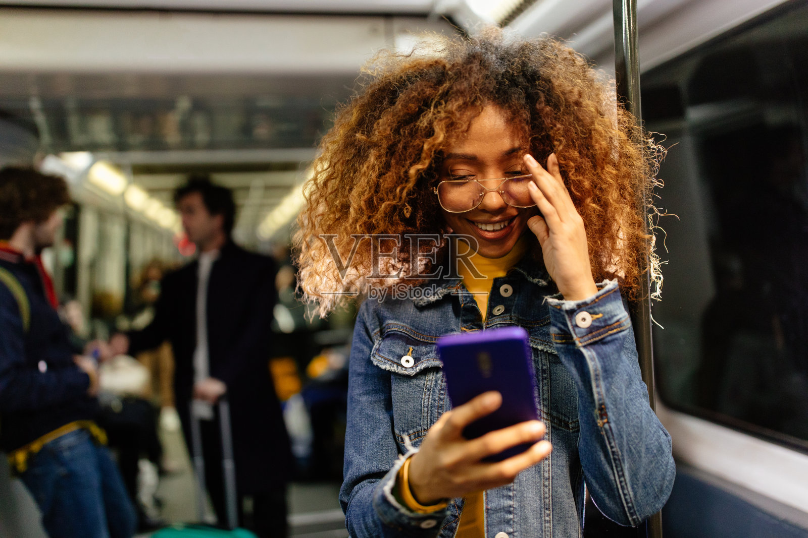 年轻的黑人女性，留着非洲式发型，在火车上用智能手机照片摄影图片