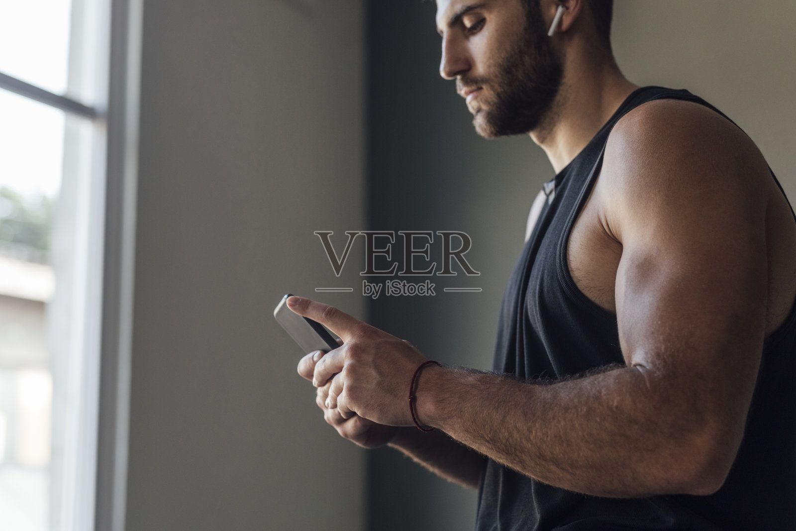 英俊的运动员与无线耳机听音乐和短信在他的手机锻炼后照片摄影图片