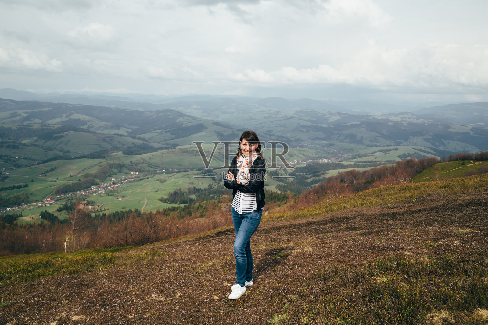 快乐微笑的女游客穿着蓝色牛仔裤和条纹衬衫徒步登山，享受宁静和自然的和谐照片摄影图片