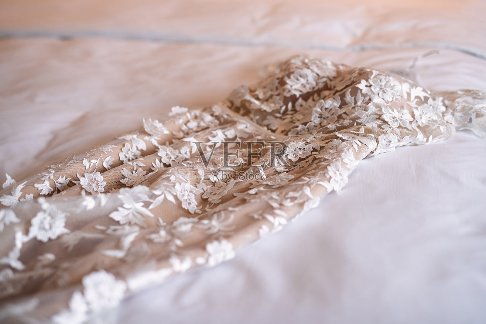 婚纱躺在床上，白色的被褥，在新娘的房间里，婚礼前的早上，婚纱上装饰着织物花，照片摄影图片