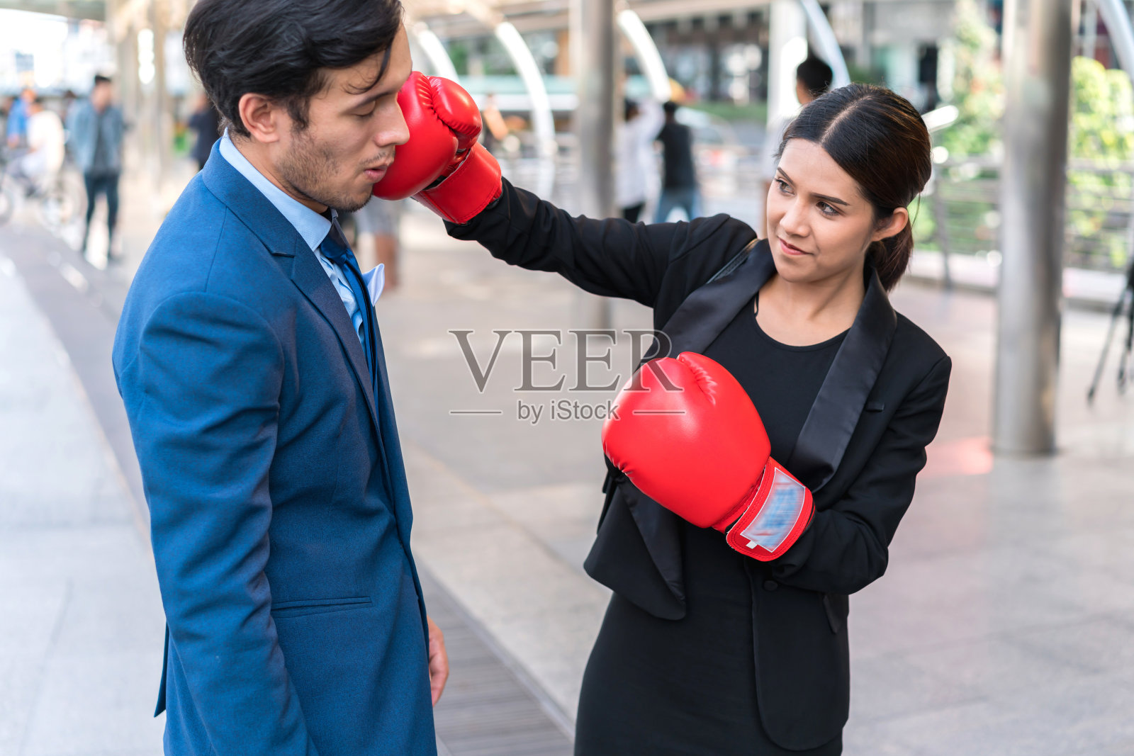 商人们戴着红手套打架。女人给男人一拳。商业竞争的概念。照片摄影图片