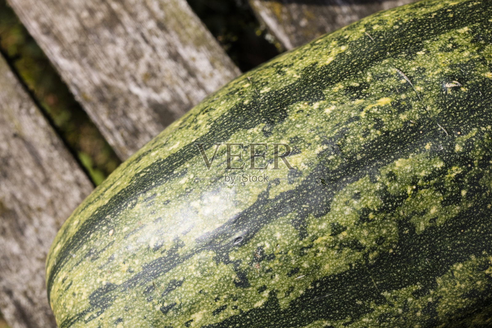 在一个阳光明媚的日子里，在旧的木制背景上的绿色南瓜的细节照片摄影图片