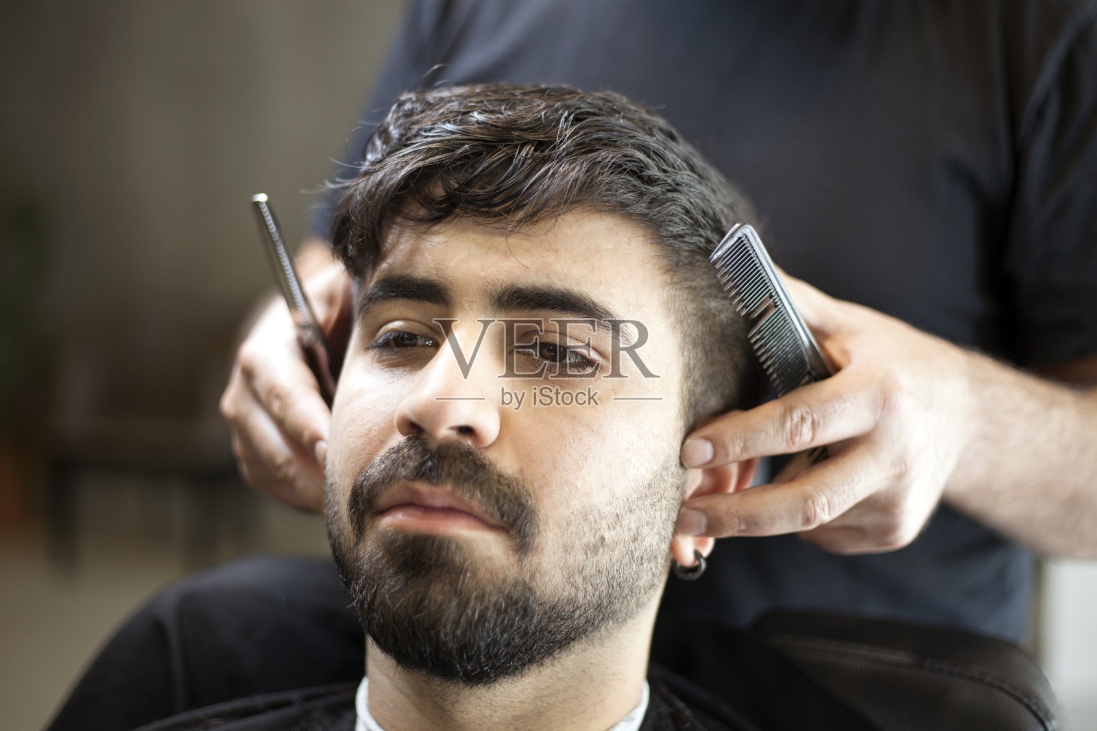 男发型师服务客户，用机器和梳子理发。照片摄影图片