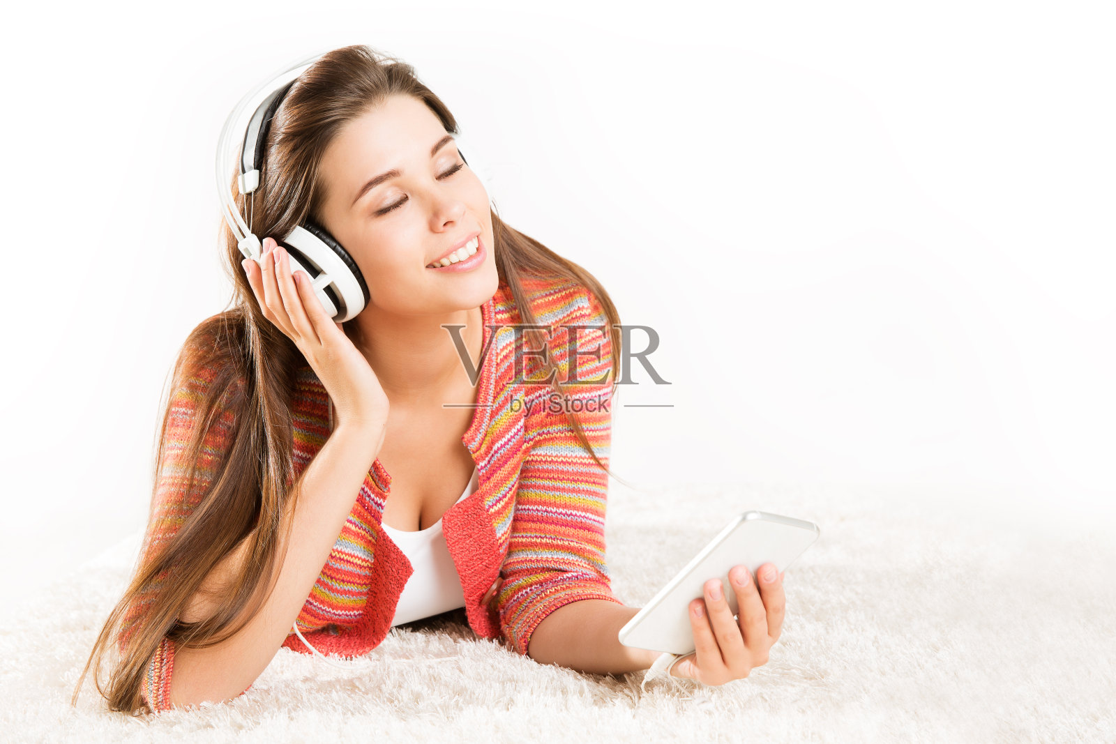 戴着耳机在智能手机上听音乐的女人，美丽快乐的女孩用手机放松的白色照片摄影图片