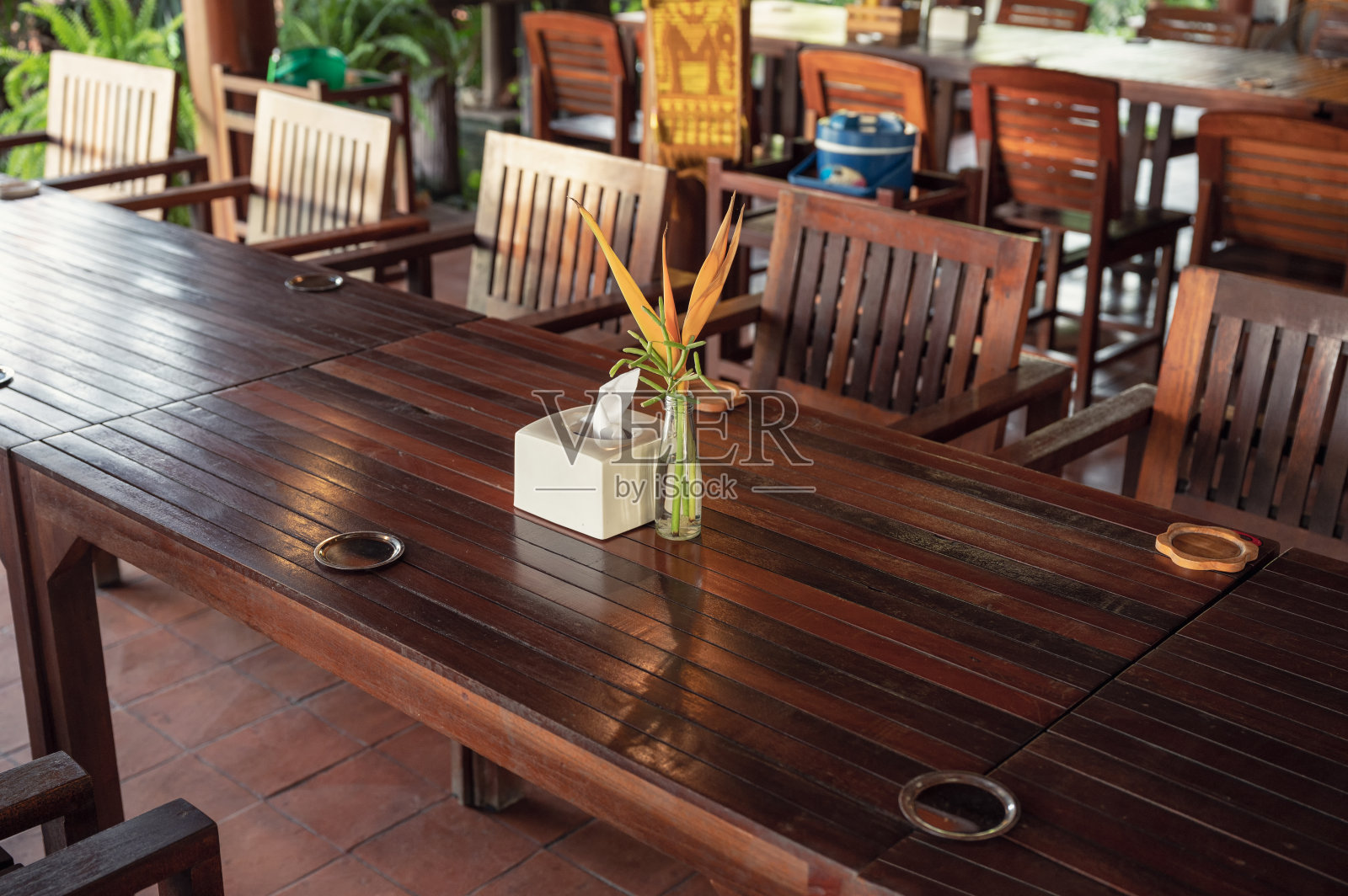 在餐厅准备木质餐桌和椅子，花瓶上插花和餐巾照片摄影图片