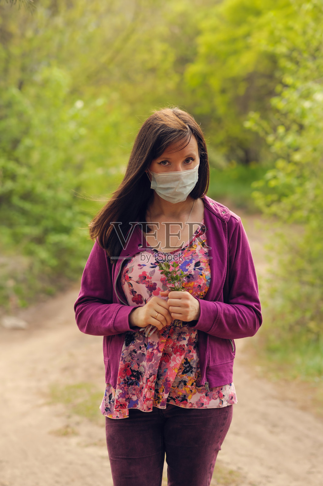 一位戴着医用口罩的妇女站着，焦虑地看着镜头照片摄影图片