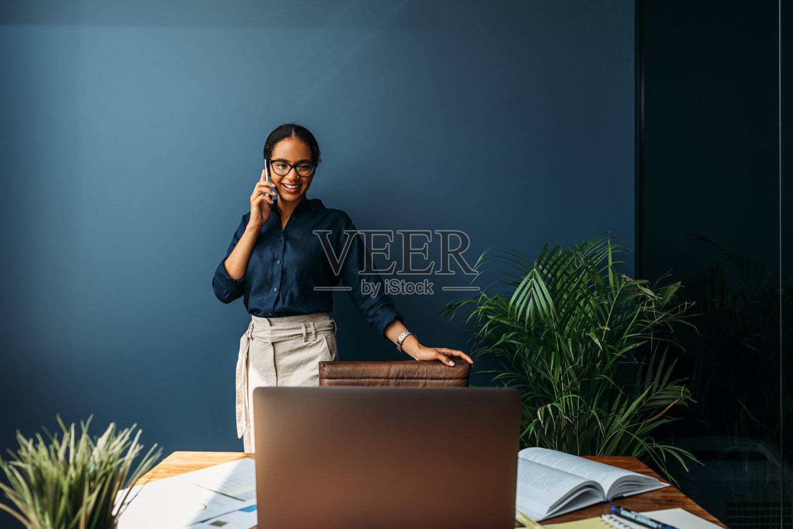 一名女性企业家倚靠在家庭办公室的椅子上，同时在看笔记本电脑的屏幕照片摄影图片