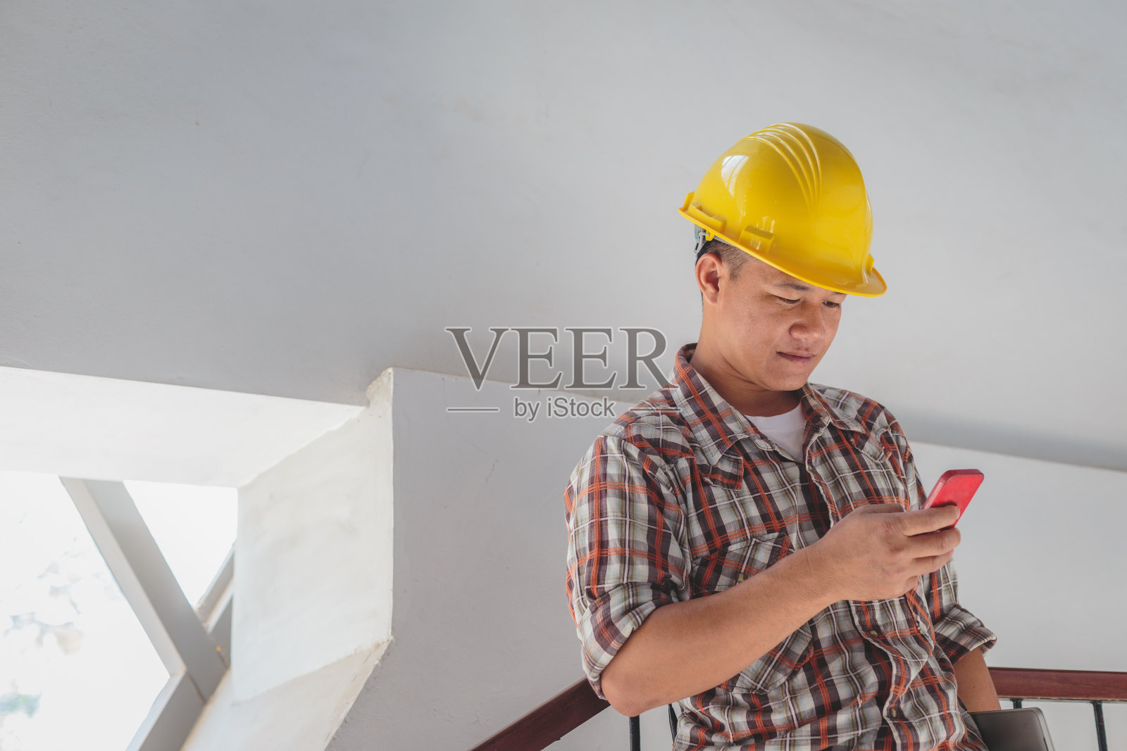 亚洲建筑工程师在安全帽中使用亚洲建筑工程师在安全帽中使用手机在施工现场，工程师在施工现场检查建筑施工项目照片摄影图片