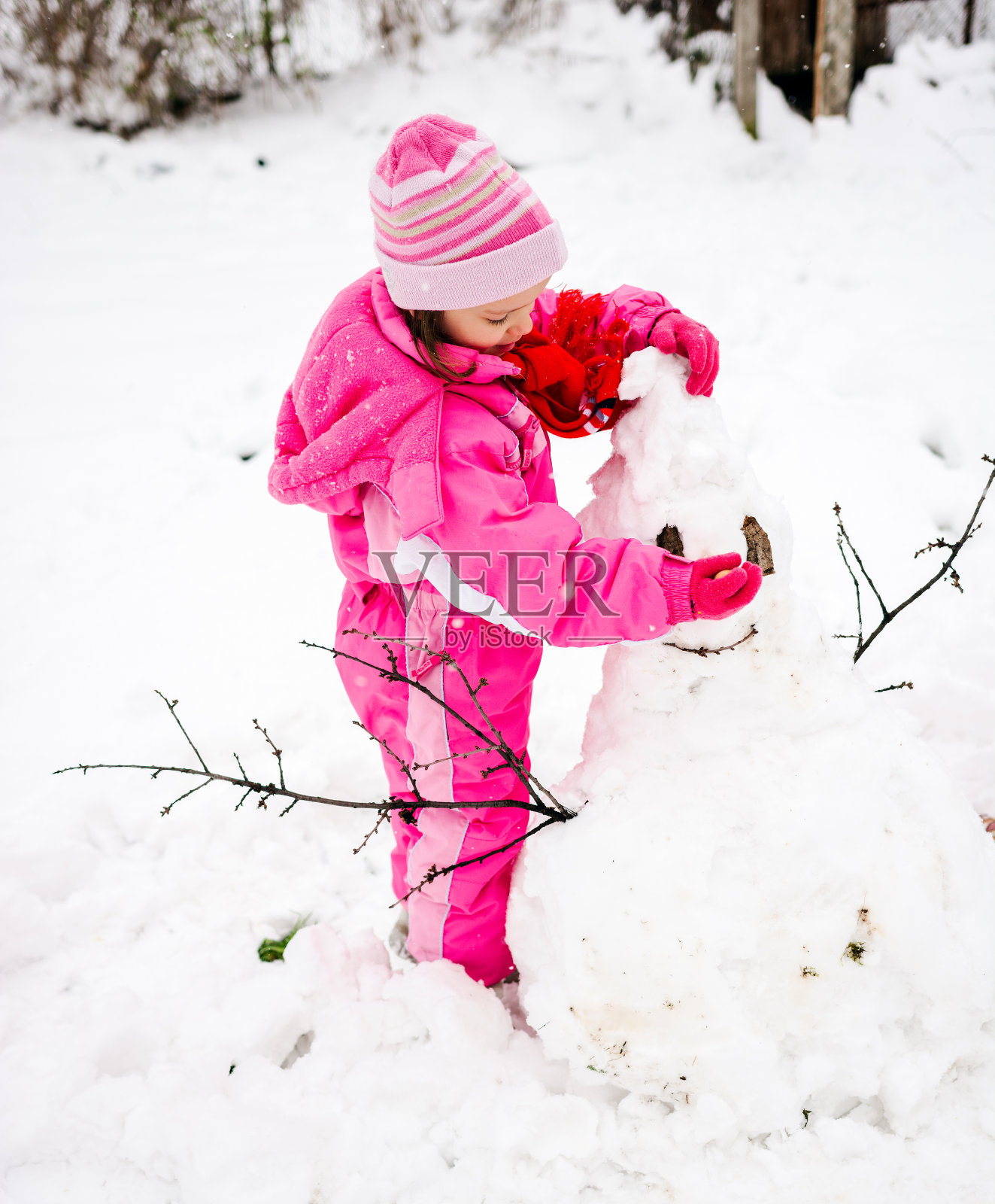 小女孩在院子里堆雪人照片摄影图片