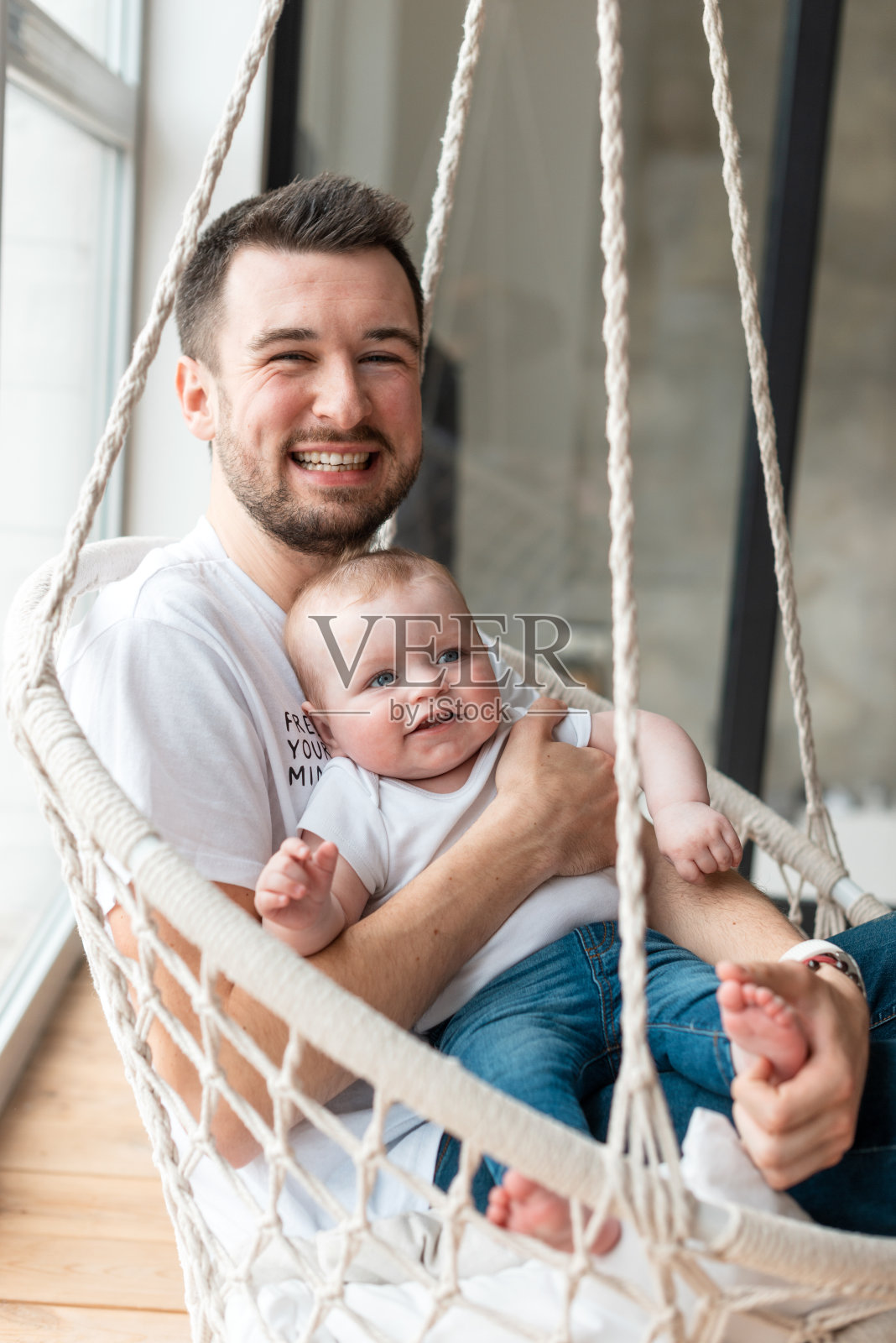 微笑，快乐的父亲抱着他的小，美丽的女儿坐在吊椅上照片摄影图片