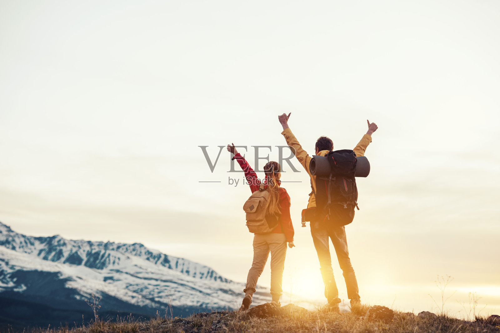 两个快乐的徒步旅行者在山上看日落照片摄影图片