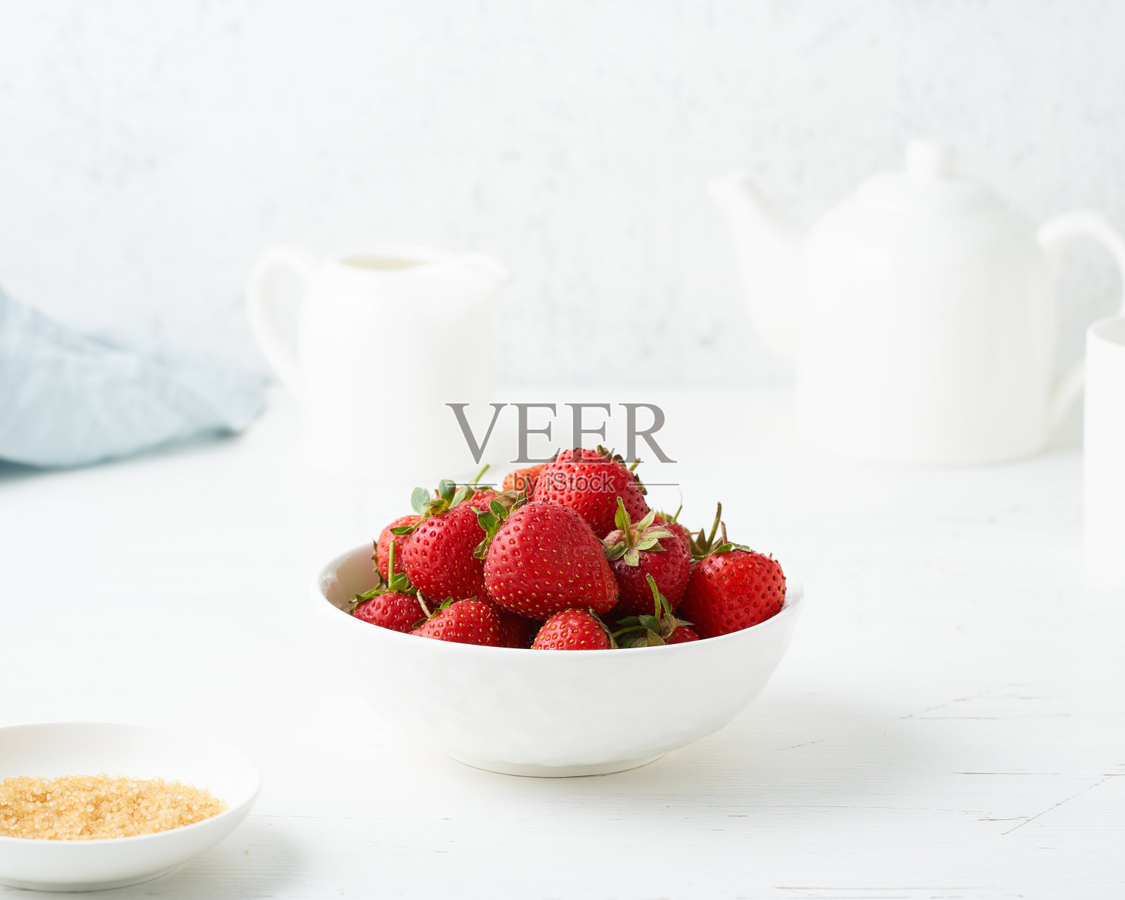 草莓在白色的碗里，在白色的桌子上，早晨的早餐，夏天的食物照片摄影图片