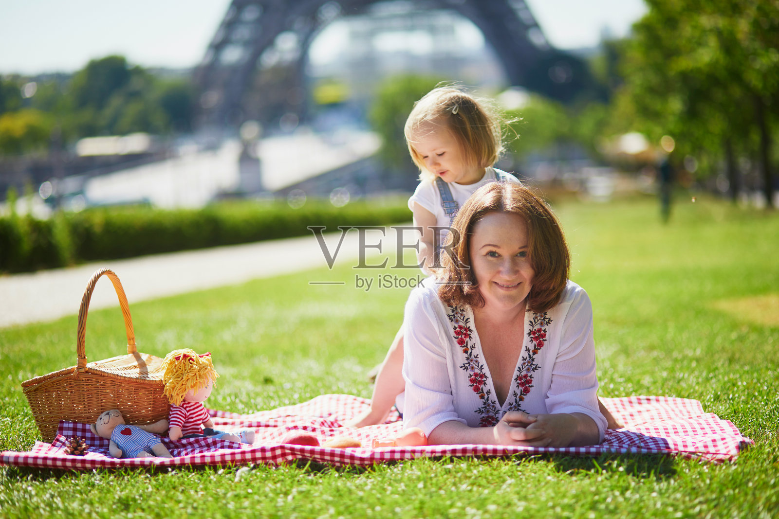 年轻女子与蹒跚学步的女孩在巴黎埃菲尔铁塔附近野餐照片摄影图片