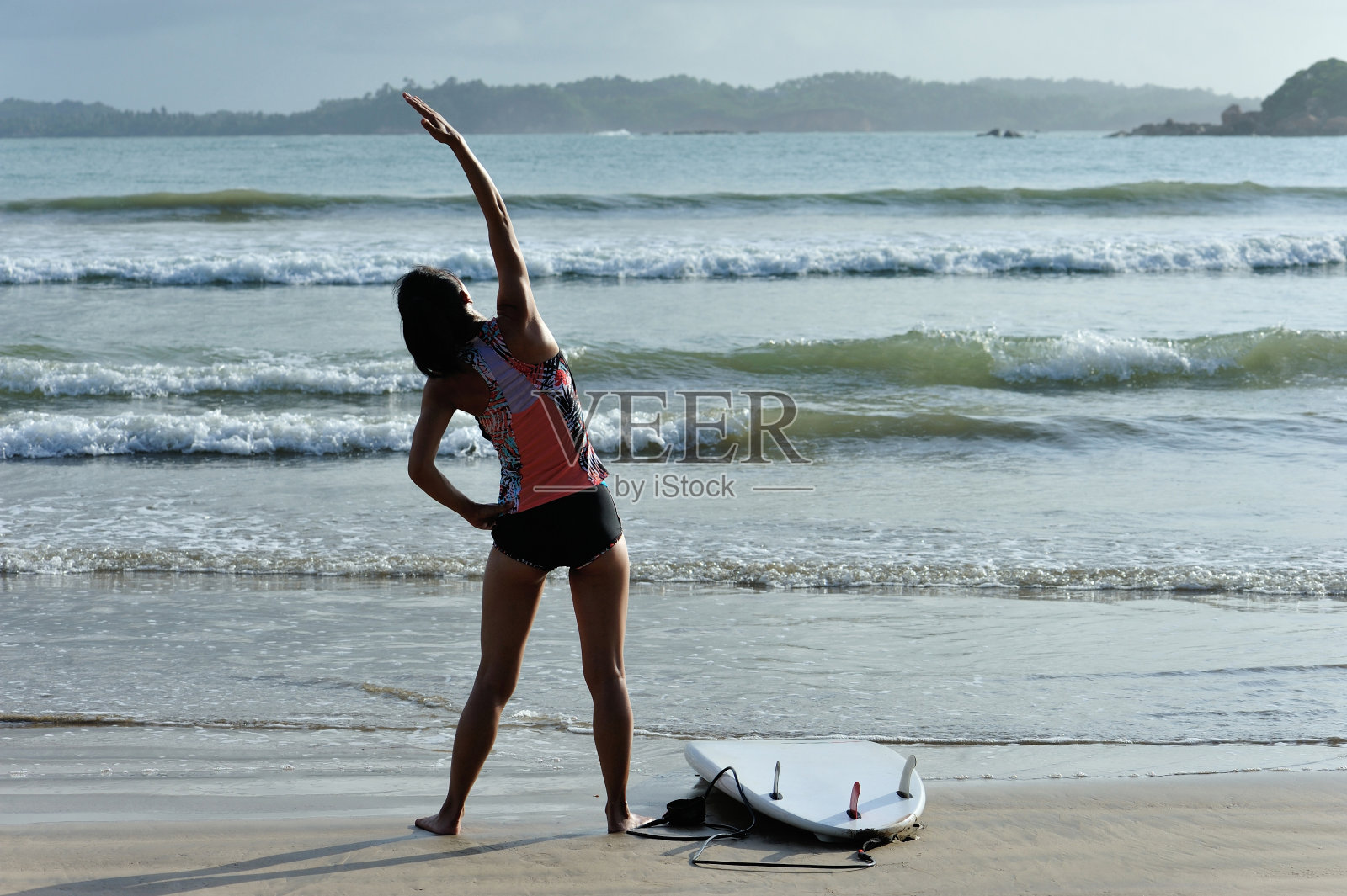 年轻女子冲浪者在海滩上热身照片摄影图片