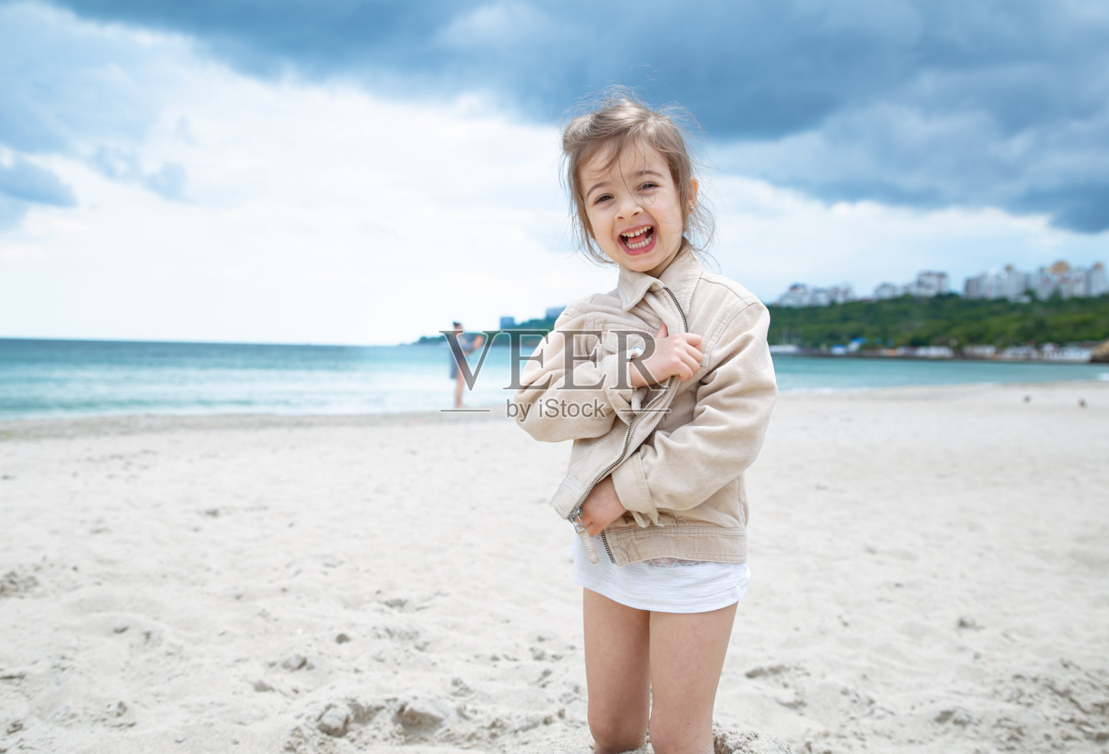 一个阳光明媚的日子，可爱的小女孩在海边的沙滩上跑步照片摄影图片