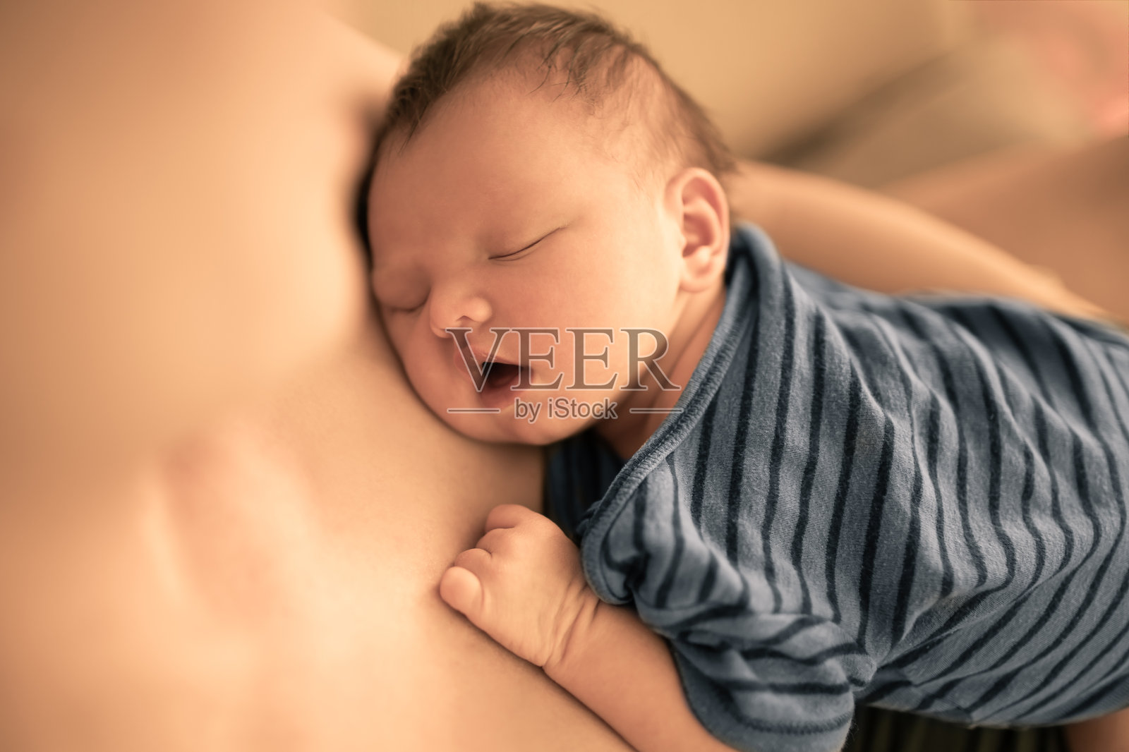 可爱的新生婴儿睡在妈妈的怀里。照片摄影图片