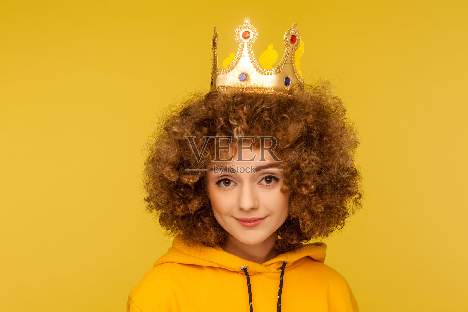 我是女王!可爱的快乐的卷发女人的特写头戴皇冠和微笑，自信照片摄影图片