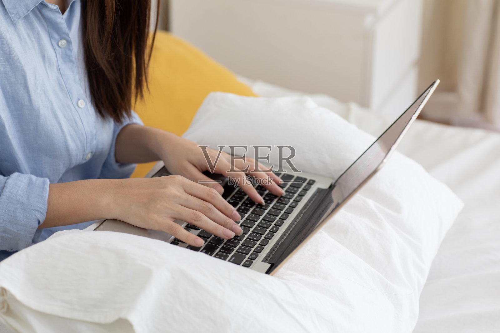 裁剪的照片，漂亮的黑发女人打字电子邮件笔记本电脑，而坐在卧室照片摄影图片