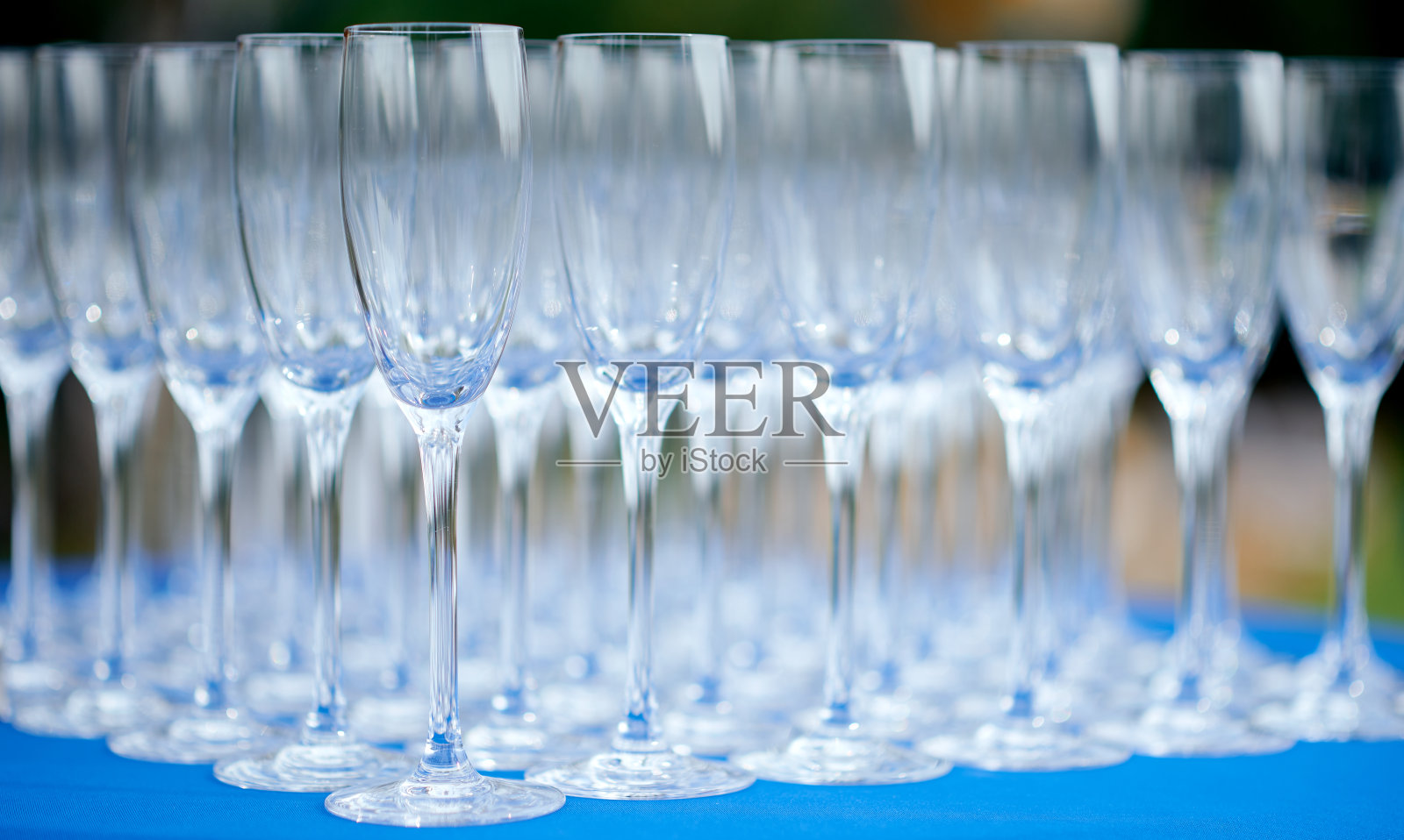 蓝色的桌子上放着一只盛满葡萄酒杯的玻璃杯照片摄影图片