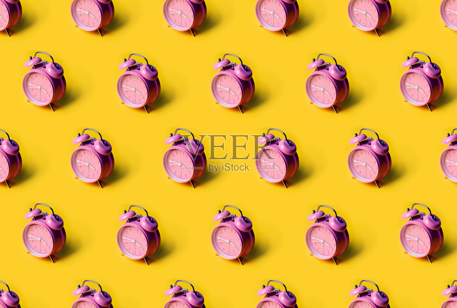 粉黄色背景上的粉色闹钟的创意布局。最小的概念。照片摄影图片