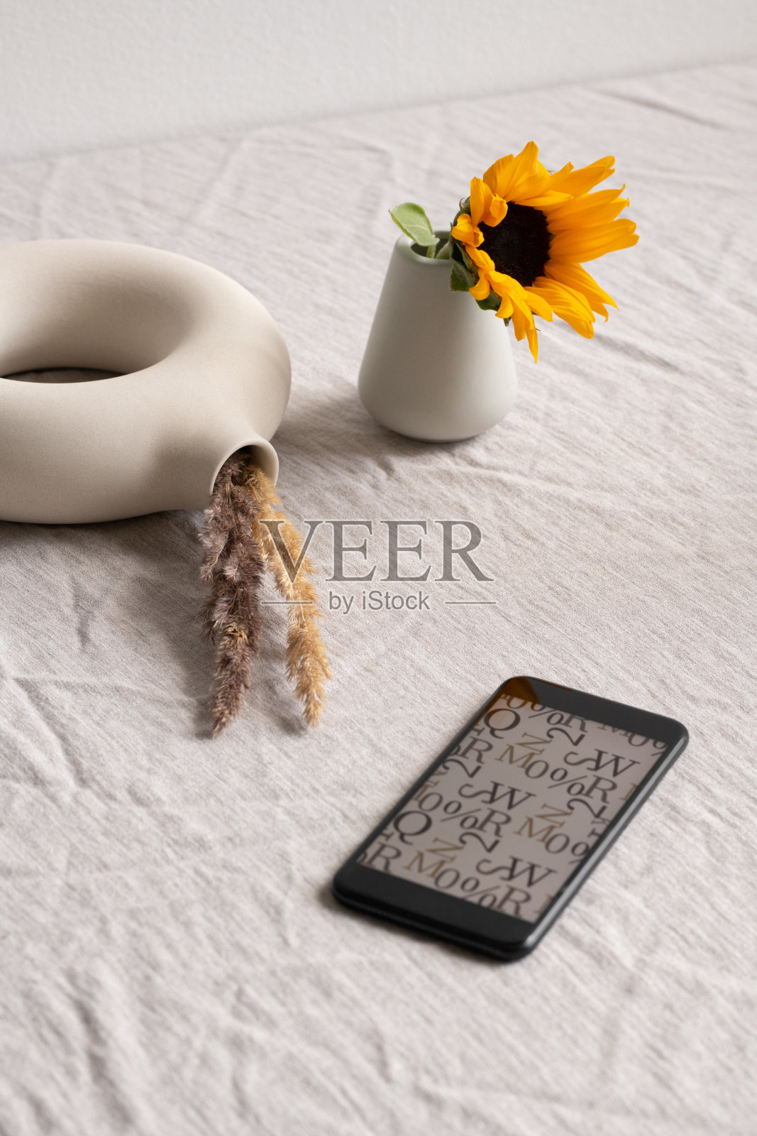 智能手机，陶瓷玻璃里的向日葵和带有干穗的环形花瓶照片摄影图片