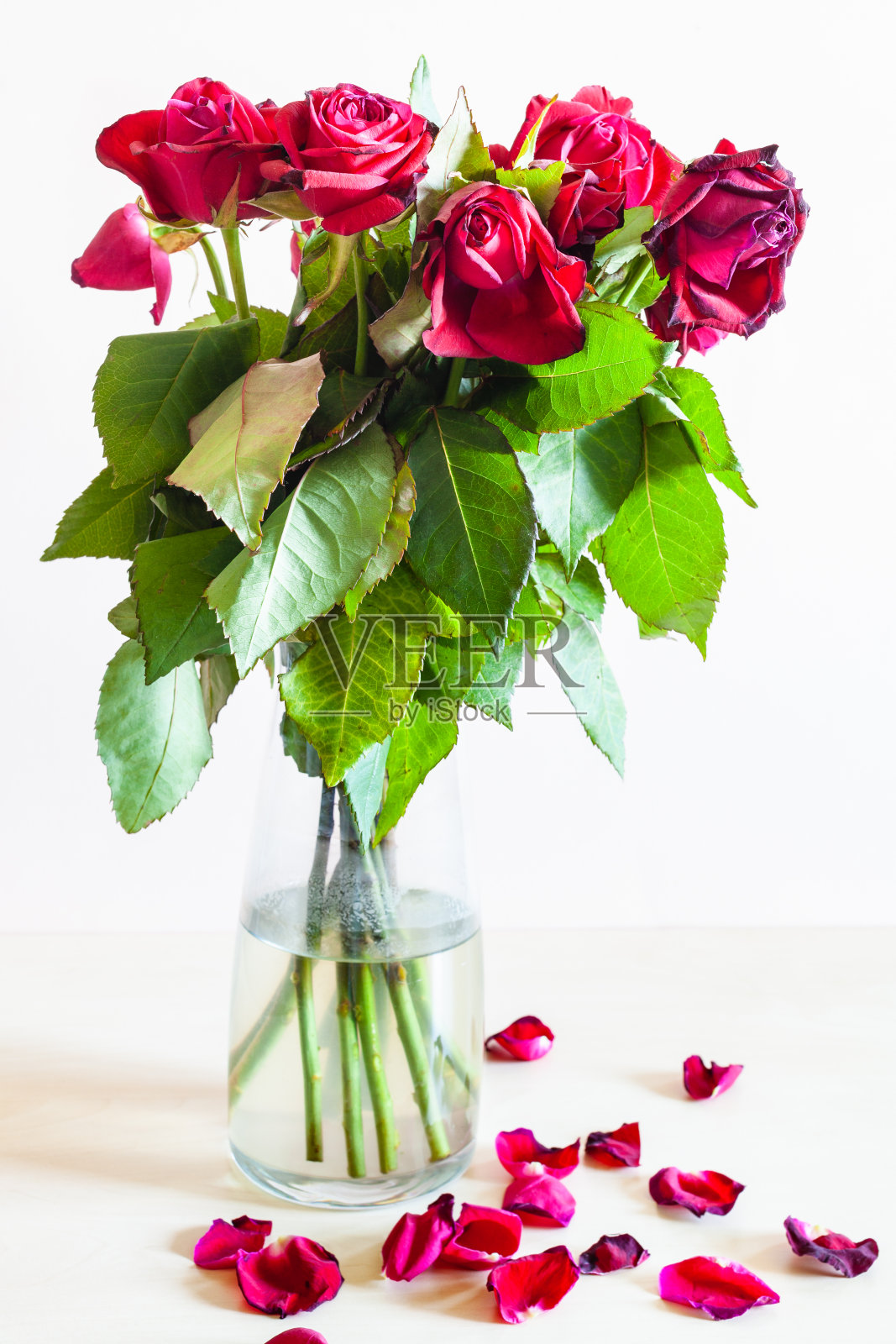 侧面的花束枯萎的红玫瑰在花瓶照片摄影图片