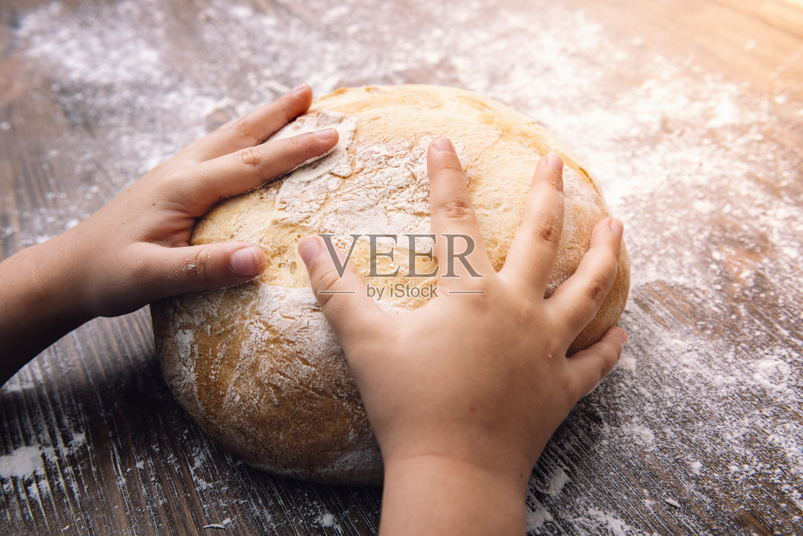 一个孩子的手放在一块乡村面包上照片摄影图片