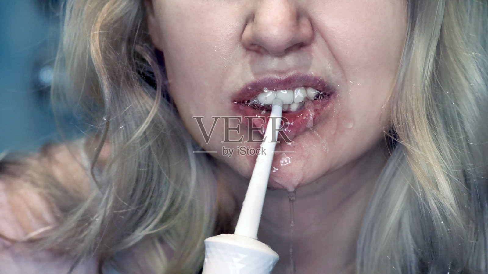 年轻女子用口腔冲洗器清洁牙齿。照片摄影图片