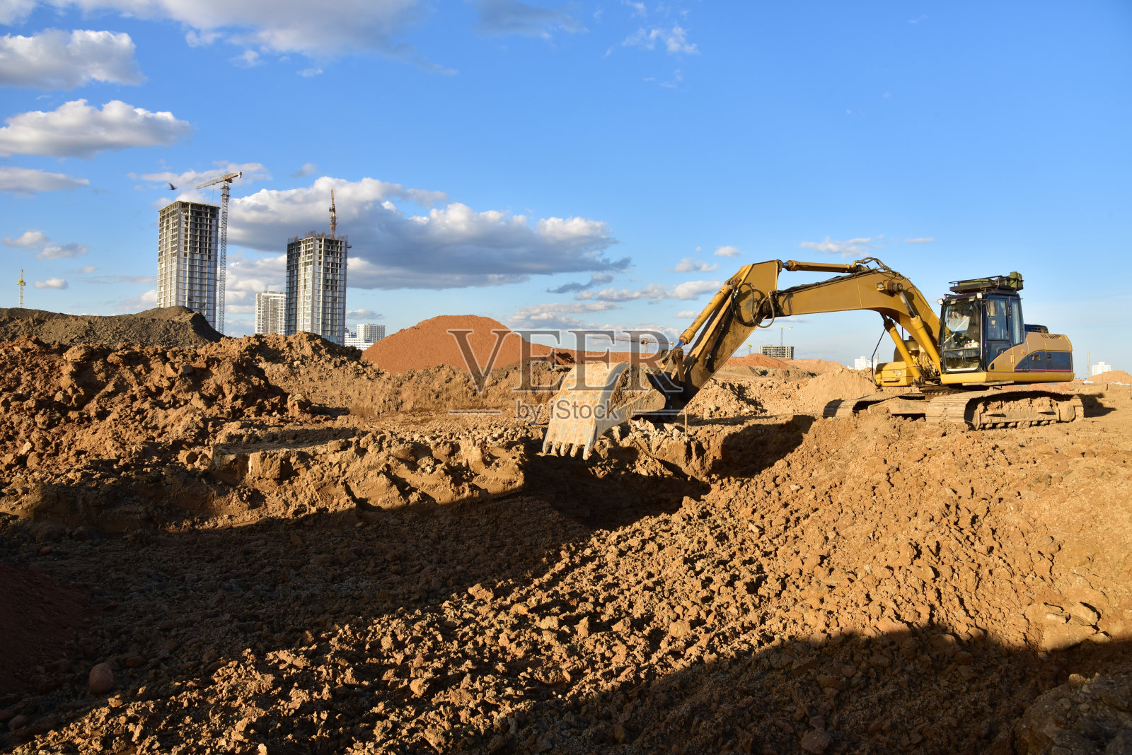 用挖掘机挖坑地基。在开挖和回填土到要求的深度的土方工程，以建设壕沟照片摄影图片