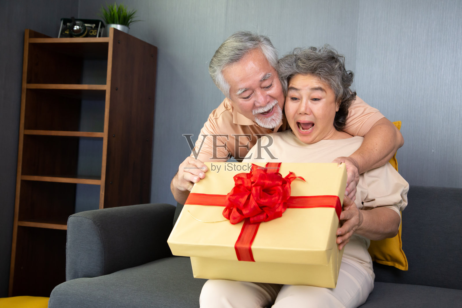亚洲资深夫妇与礼品盒在家里，周年或圣诞假期的概念照片摄影图片