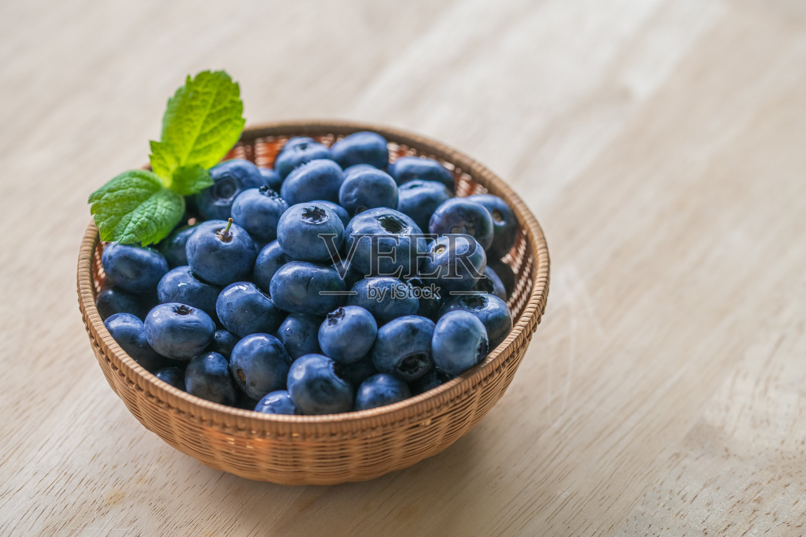 新鲜成熟的蓝莓在篮子里的木制背景。照片摄影图片