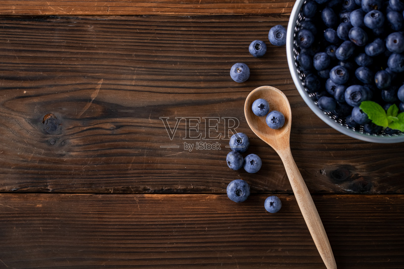 新鲜成熟的蓝莓勺在木背景。照片摄影图片