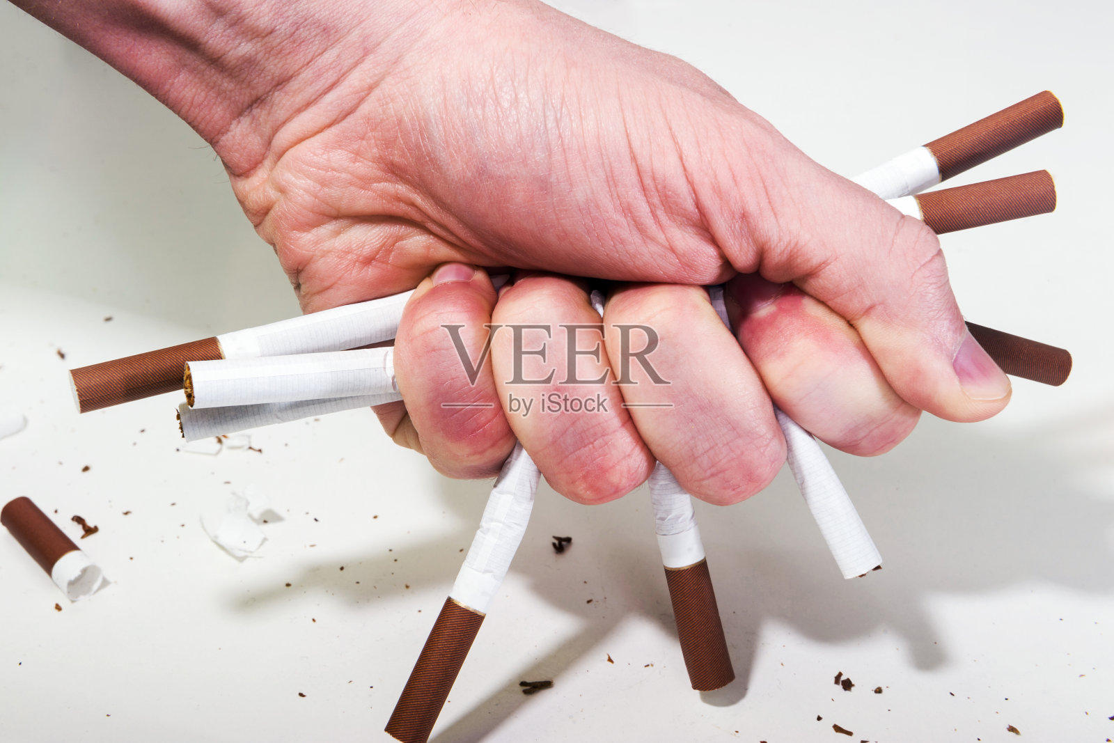 一个男人的手在白色的背景上破坏、揉皱香烟，这就是戒烟的概念。照片摄影图片