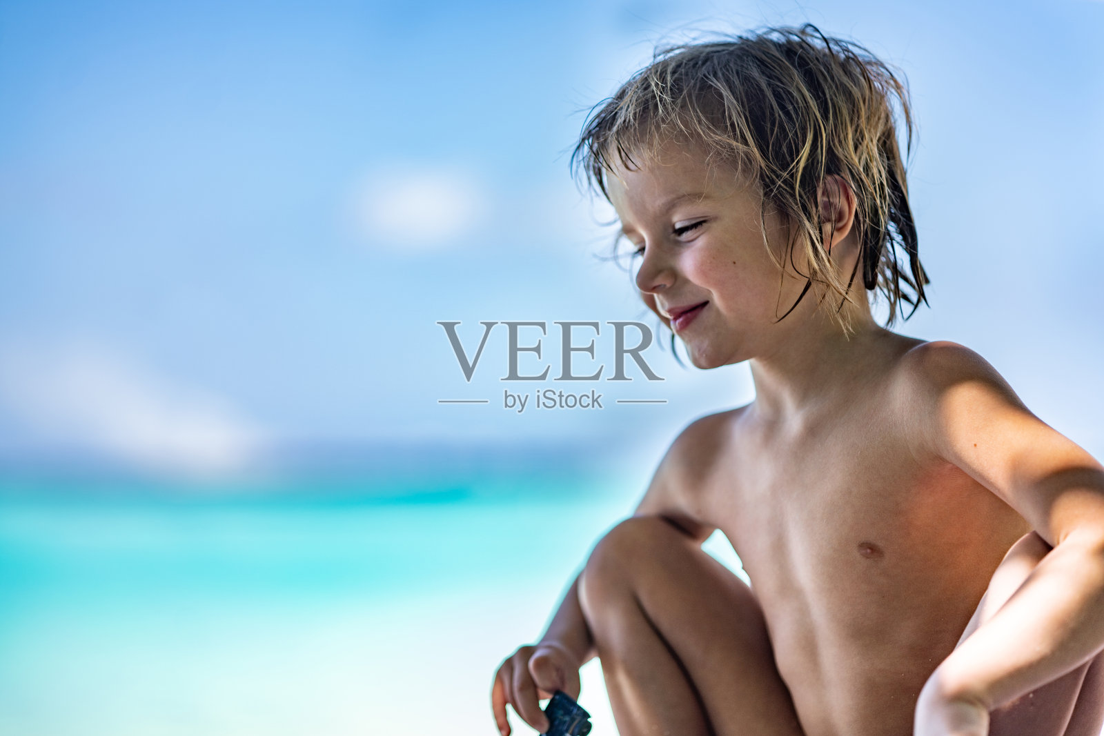 海滩上微笑的小男孩的特写照片摄影图片