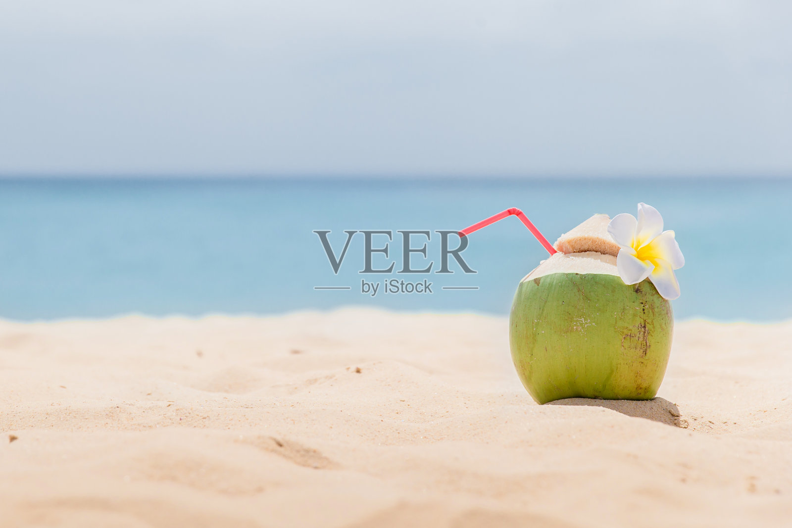 新鲜的年轻椰子躺在沙滩上，用吸管准备喝。热带度假旅游概念照片摄影图片