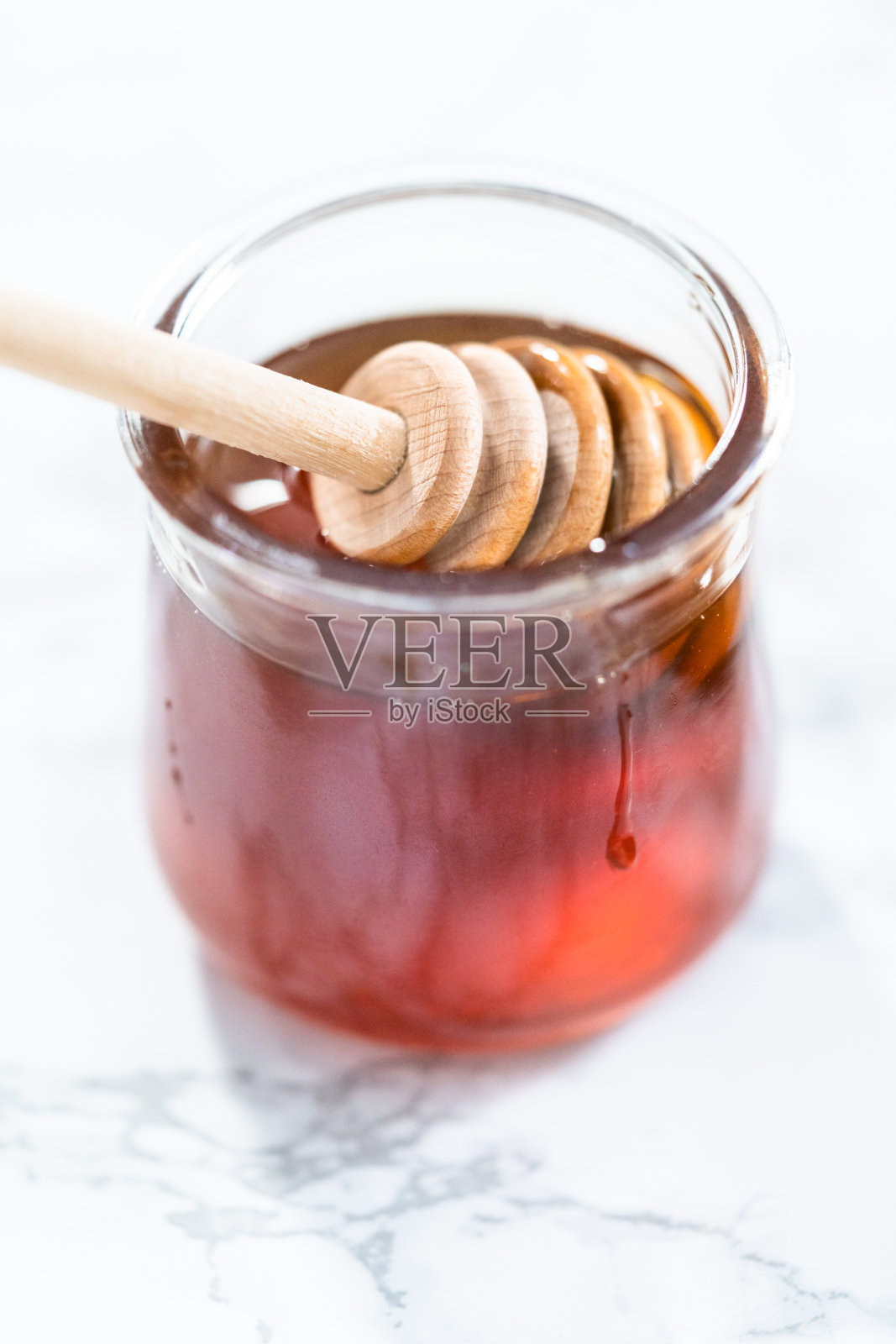 有机蜂蜜在一个小玻璃罐子和一个木制蜂蜜勺。照片摄影图片