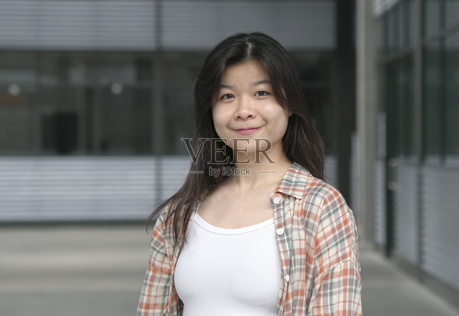 一个年轻的中国女孩的肖像。长长的黑发，对着镜头微笑。照片摄影图片