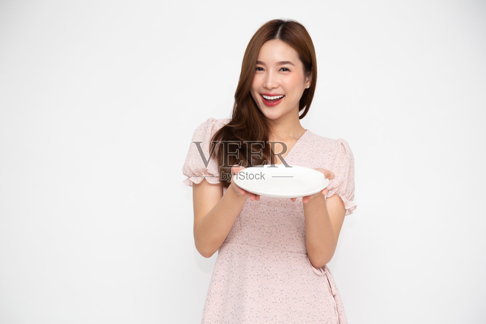 年轻的亚洲妇女拿着空的白色盘子或盘子孤立在白色的背景照片摄影图片