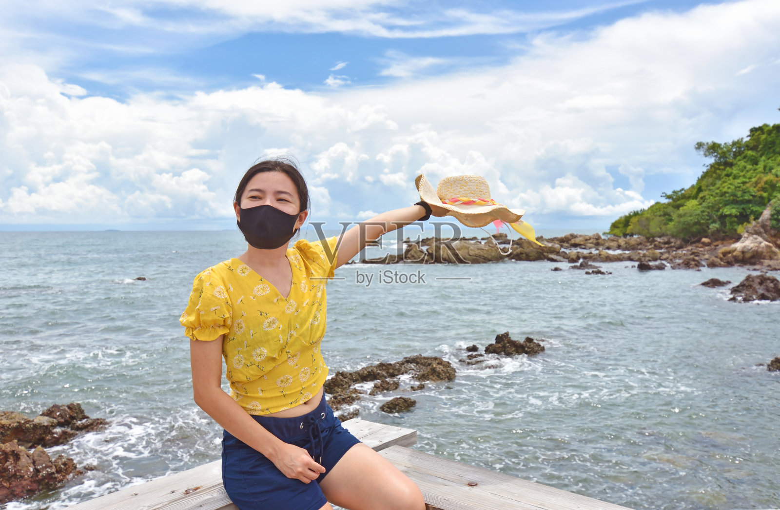 年轻女子兴高采烈地在阳光下佩戴防护口罩，因冠状病毒，新常态概念。照片摄影图片