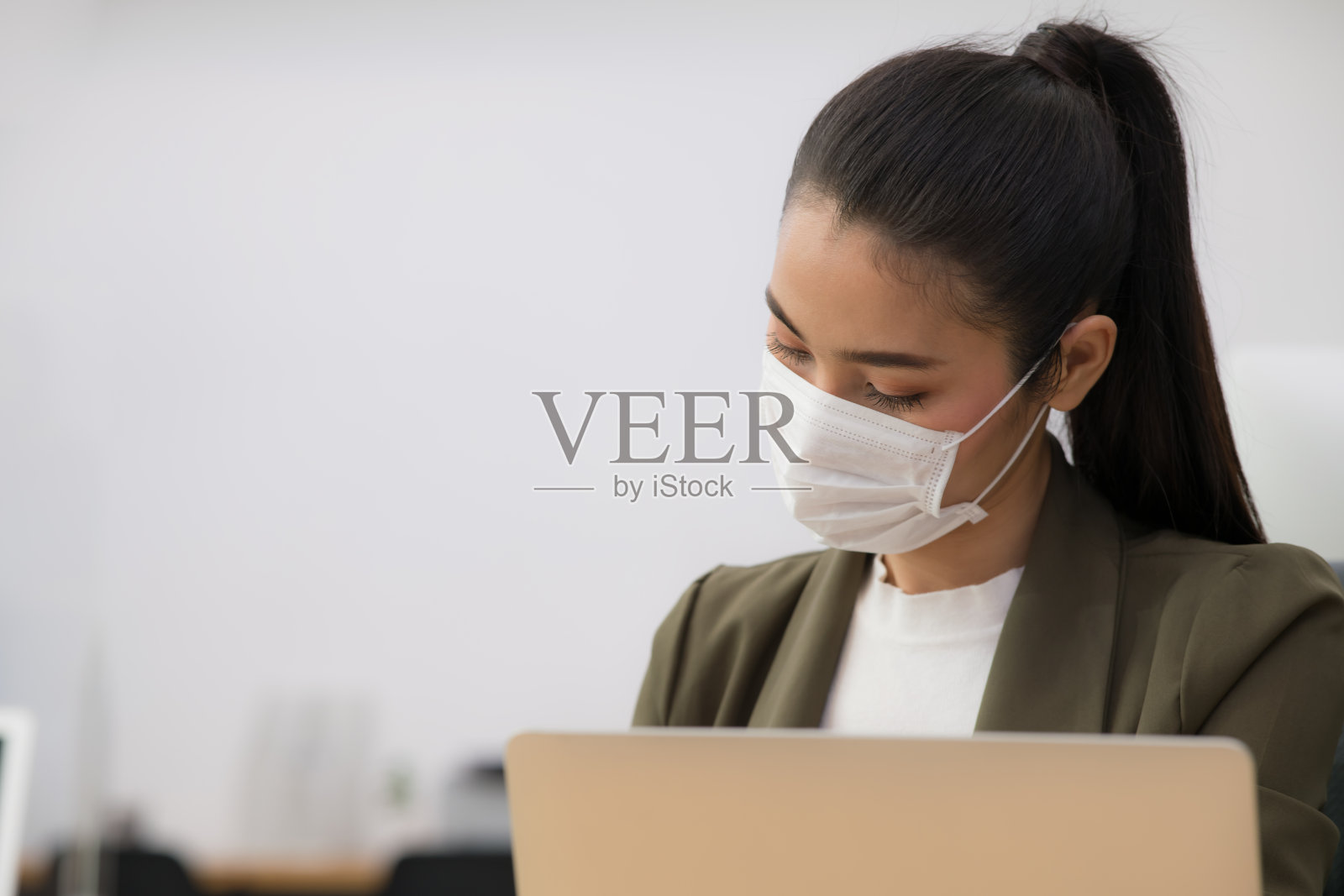 在新冠肺炎大流行期间，亚洲女性办公室职员戴着口罩在新常态办公室工作并保持社交距离的肖像照片摄影图片