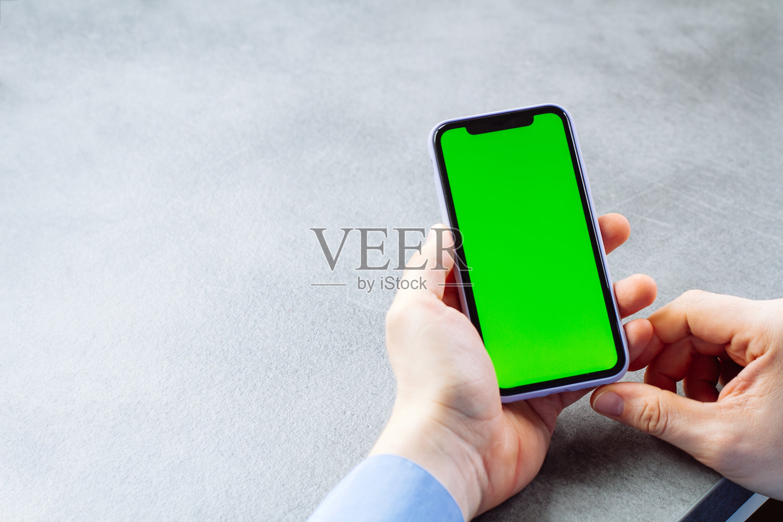 男子触摸并看着绿色屏幕的智能手机屏幕。屏幕上的色度键在商人手中照片摄影图片