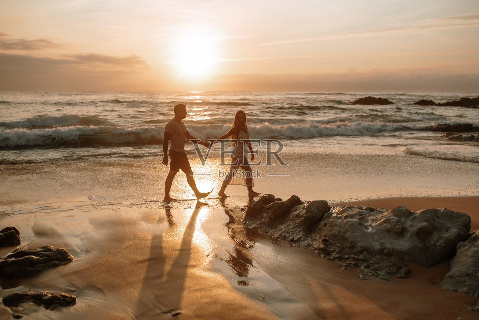 一对年轻夫妇在海滩上牵着手散步照片摄影图片