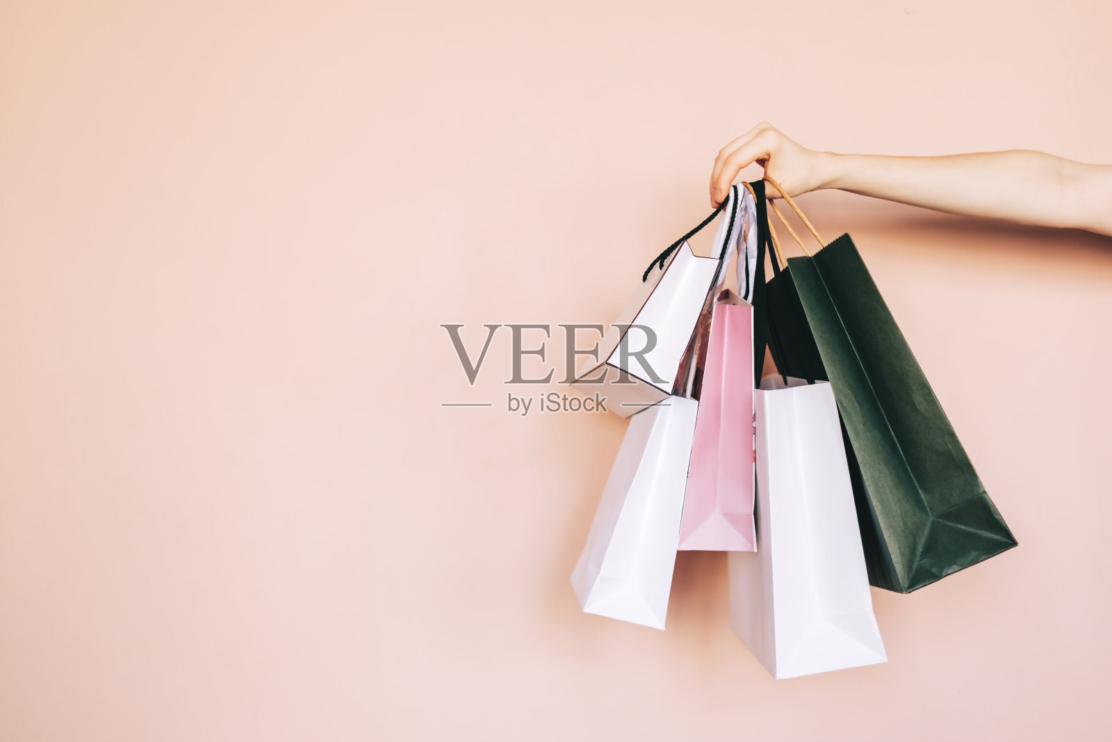 购物袋在手中孤立的米色柔和的背景。购物的概念。照片摄影图片