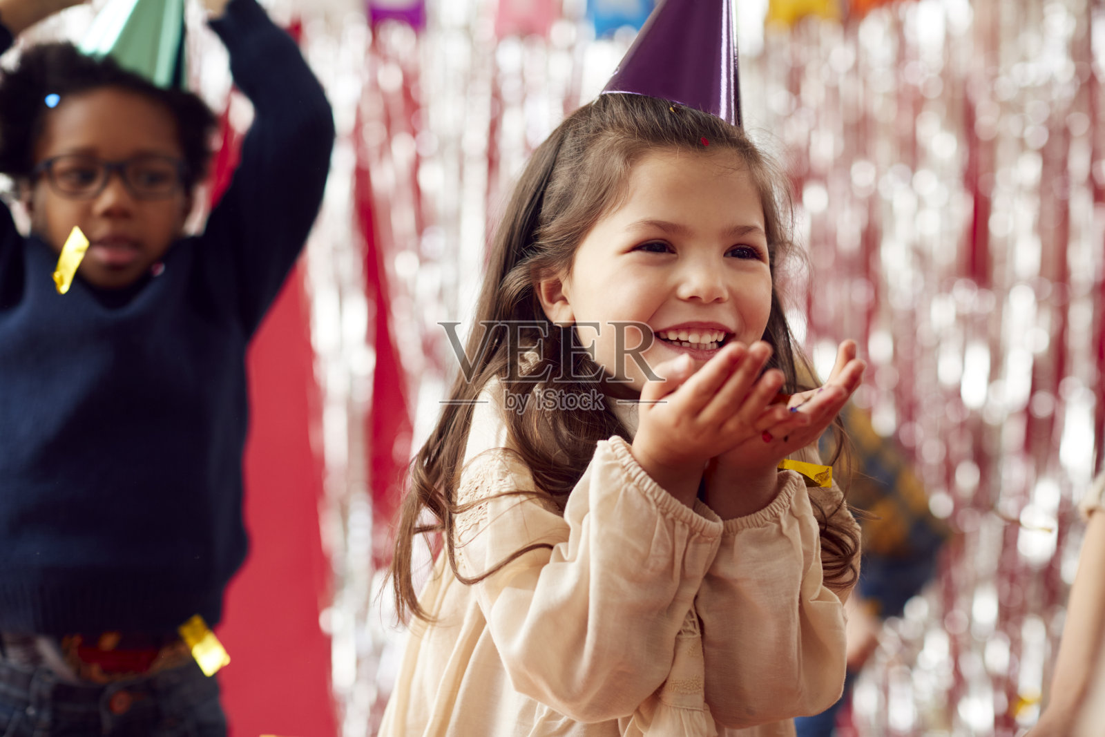 女孩在派对帽子庆祝在生日派对吹一把金色的五彩纸屑和闪光照片摄影图片