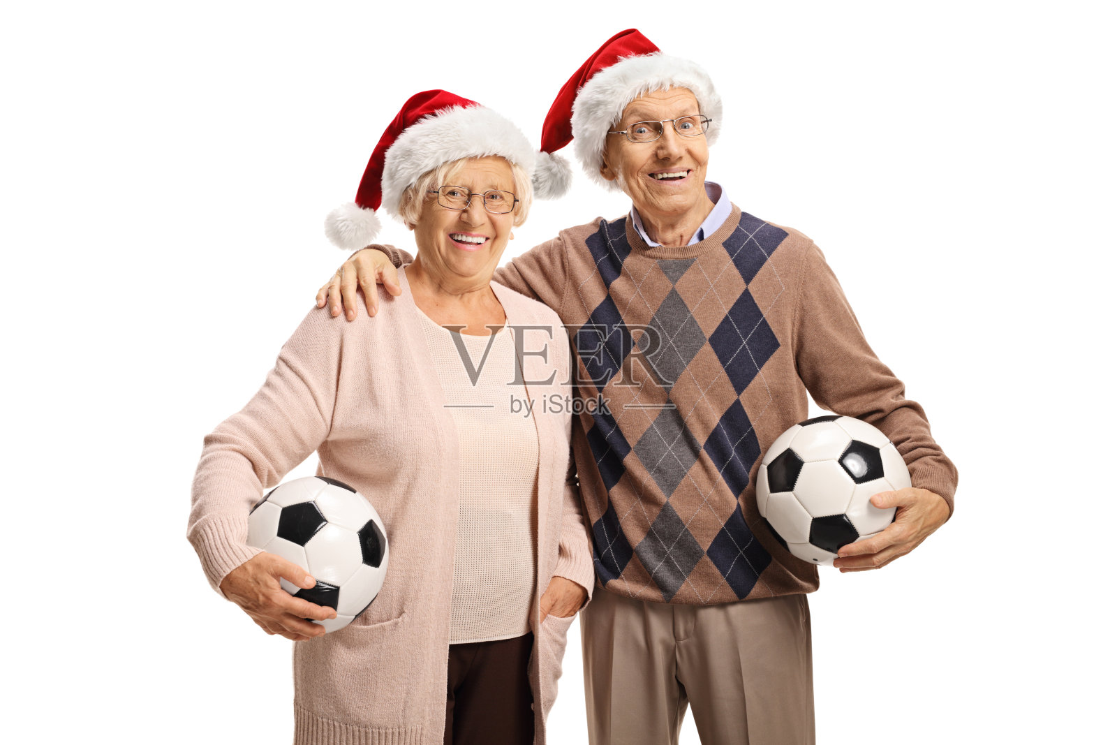 老夫妇戴着圣诞老人帽，拿着足球照片摄影图片