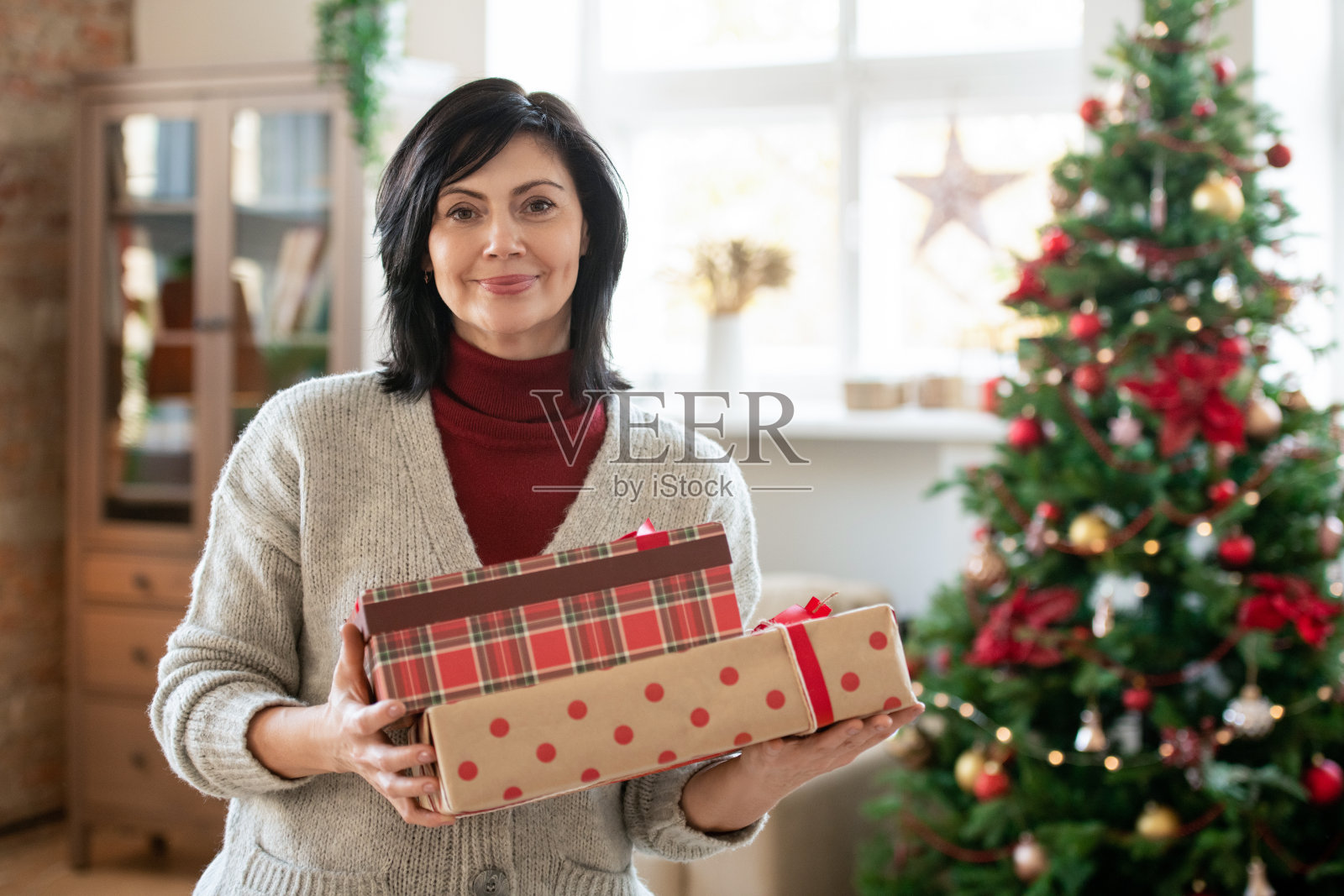 快乐成熟的黑发女性在休闲装持有一堆礼品盒照片摄影图片