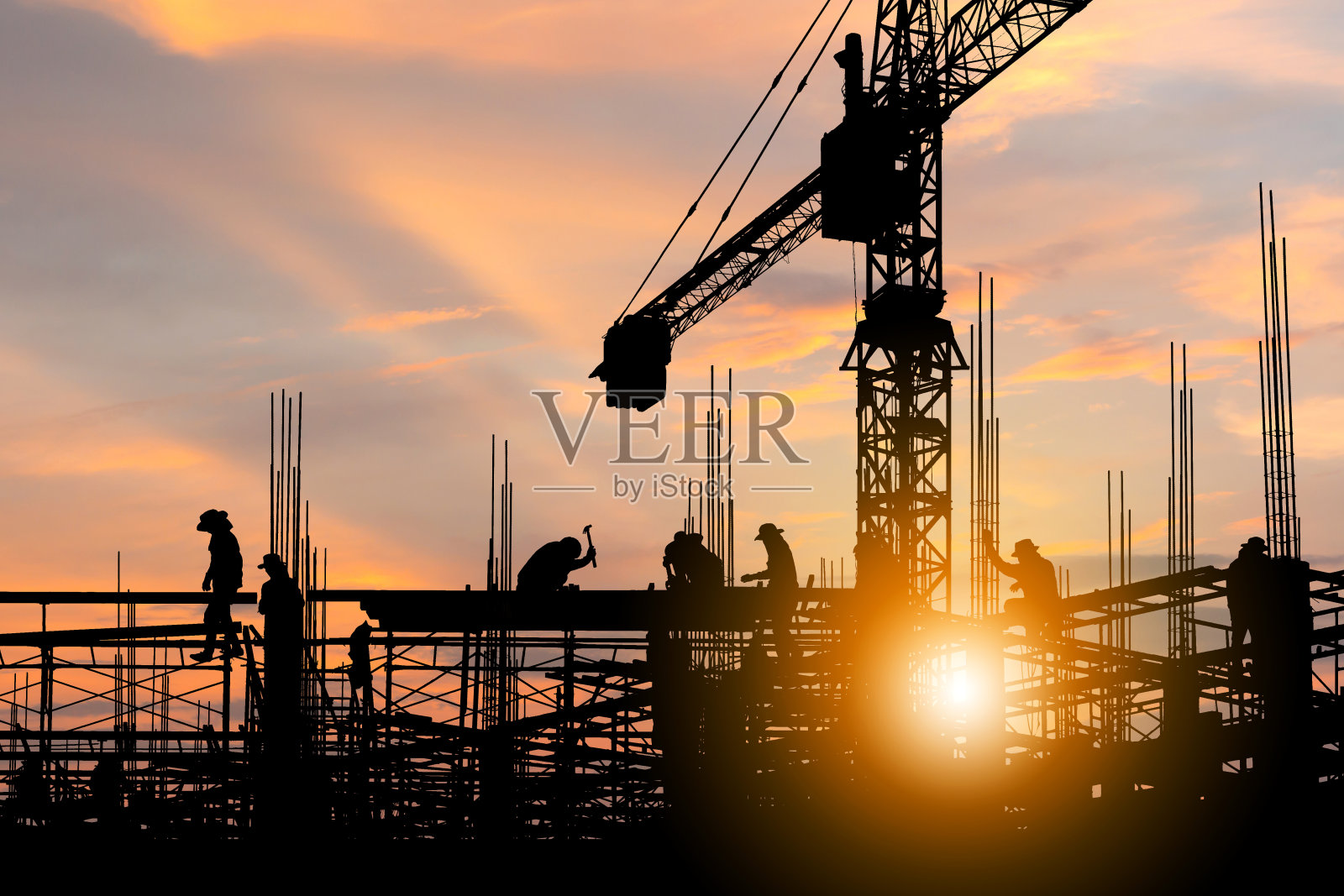 日落时分，工程师和工人在建筑工地背景下检查工程的剪影照片摄影图片