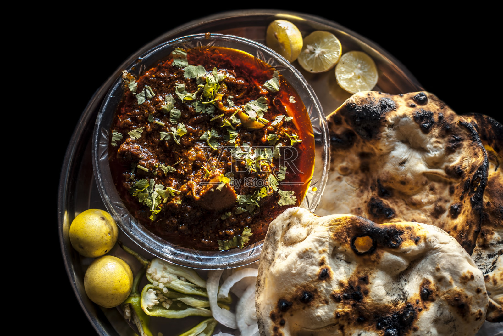 一份阿卡里鸡和印度烤炉，配上一些辣椒，洋葱和柠檬。照片摄影图片