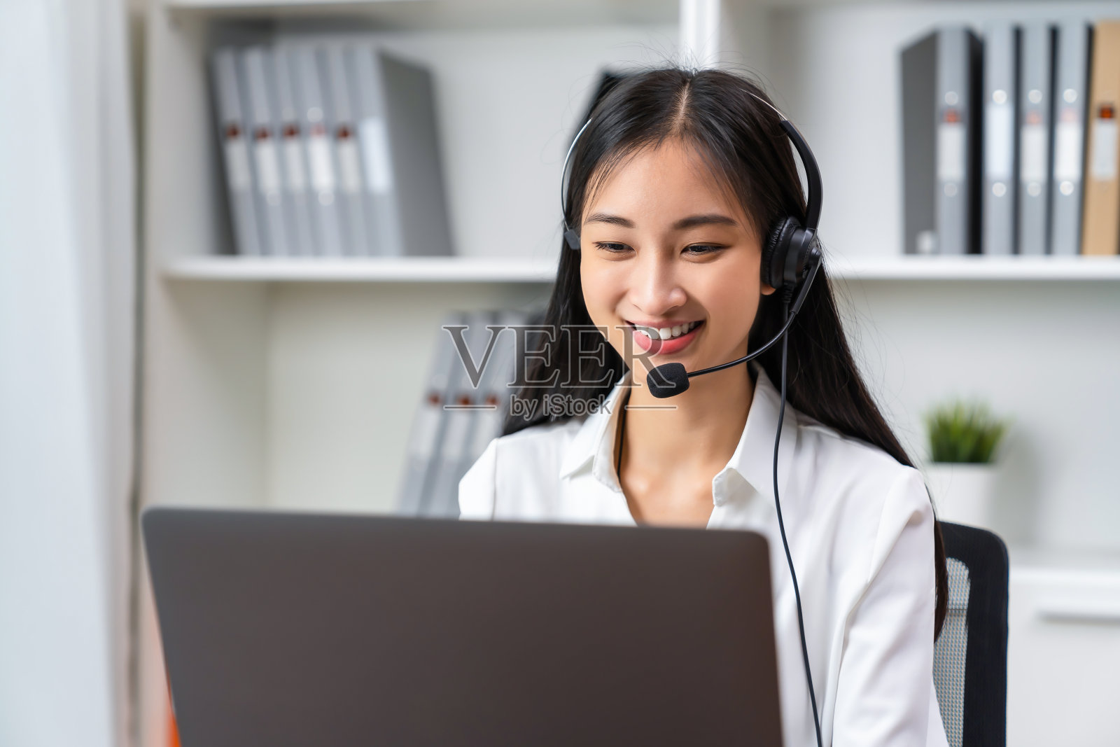 亚洲商务女性戴着耳机，通过在线客户支持进行电话营销。照片摄影图片